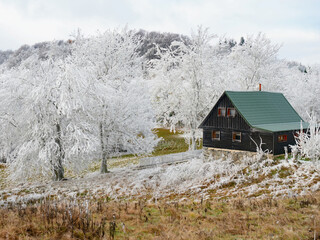 Cottages in early winter scenery with amazing hoarfrost cover in hills a