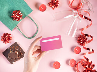 Woman's hand holding credit card above pink background