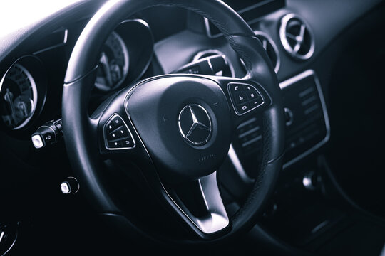 Steering wheel of a Mercedes-Benz vehicle highlighted in the photo for the company logo.