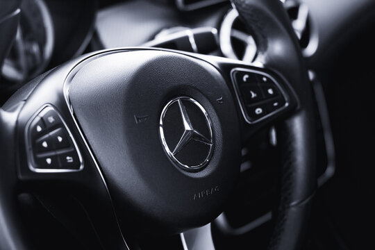 Steering wheel of a Mercedes-Benz vehicle highlighted in the photo for the company logo..