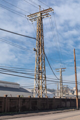 Street view of huge industrial electric power towers behind a security wall, industrial site, vertical aspect