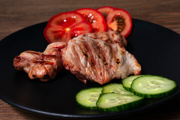 fried pork with vegetables on a black plate