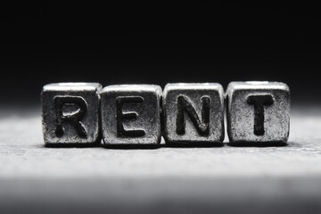 concept of rent. The inscription on metal 3D cubes isolated on a black background, grunge style