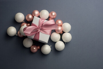 White gift with pink ribbons. Gift box isolated on gray background with snowflakes.Christmas gift boxes on gray background. Beautiful Christmas background with shiny balls and ribbons in pink color.