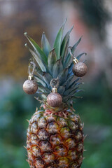 Fototapeta premium Pineapple decorated with gold Christmas baubles. Selective focus.