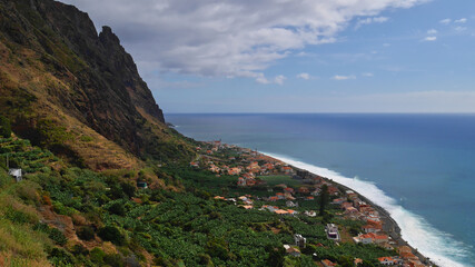 Beautiful panoramic view over small fishing village Paul do Mar on the western coast of Madeira island, Portugal with banana plantations, steep cliffs and rough Atlantic Ocean on sunny day.