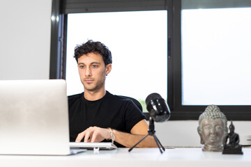 young entrepreneur works from home in his office with the computer in front of a window