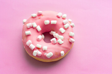 Obraz na płótnie Canvas Pink sweet donut with marshmallows on a pink background. Close-up. Flatley. Place for text and design.