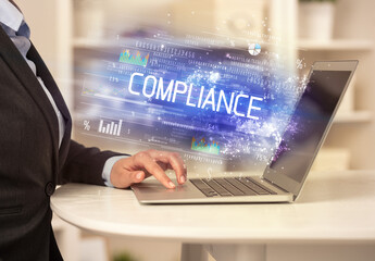 Closeup of businessman hands working on laptop with COMPLIANCE inscription, succesfull business concept