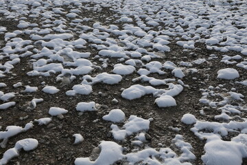 Frosty ground covered with white patches of snow