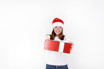 Happy pretty young woman holding a gift box over white background wearing red santa hat