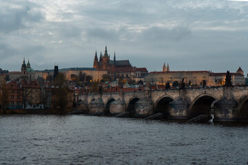 old prague castle and charles bridge and st. vita church lights from street lights are reflected on the surface of the vltava river in the center of prague at night in the czech republic