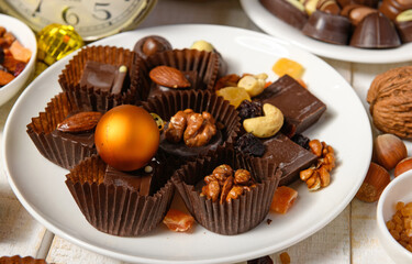 sweet food background for christmas or holiday decoration - chocolate candies, tangerines, nuts and dried fruits on white wood