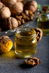 Cosmetic and therapeutic walnut oil on wooden background. Walnut oil in bottle and nuts on a dark background.