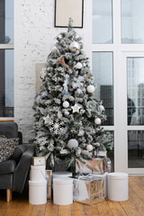 Christmas tree decorated with white toys. Decor in one color scheme. Gifts at the tree. Decorating the Christmas tree. Festive mood. Celebrate new year or christmas.Decorate the house for the holiday.