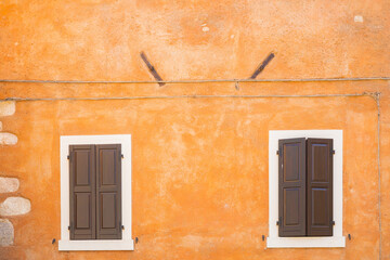 Old orange house facade, closed brown window shutters in popular touristic historic village Garda