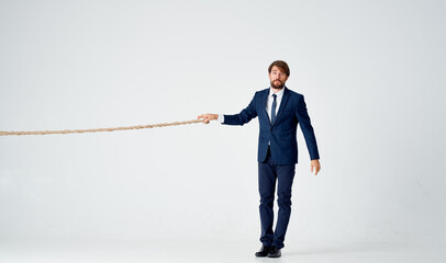 business man in a suit pulls a rope on a light background