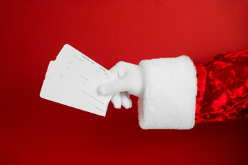Santa holding airplane boarding tickets on red background. New Year's travel concept. Sale tickets