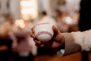 baseball ball with red stitching in the hand