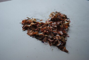Colorful heart made from a pile of colored pencil shavings on white background