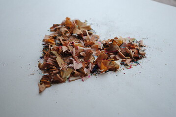 Colorful heart made from a pile of colored pencil shavings on white background