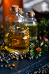 Pistacia terebinthus oil and dried seeds on dark wooden background.