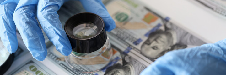 Checking American banknotes with magnifying glass closeup