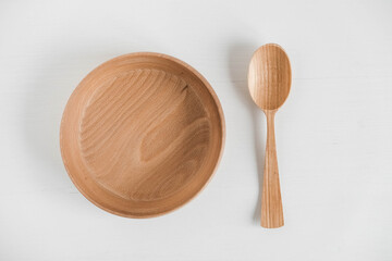 Empty wooden bowl and wooden spoon on a white background. Top view. Copy, empty space for text