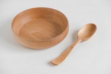 Empty wooden bowl and wooden spoon on a white background. Copy, empty space for text