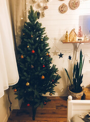 Traditional Christmas tree with red and gold baubles in festive decorated boho room