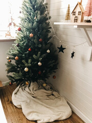 Traditional Christmas tree with red and gold baubles in festive decorated boho room