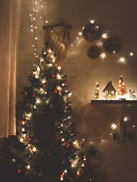 Christmas tree in festive lights with red and gold baubles in decorated dark room, christmas eve