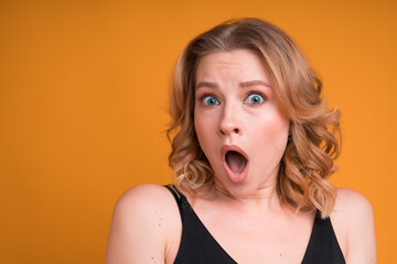 Surprised blonde woman with open mouth depicts surprise on bright background