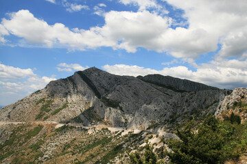 The mountainous coast of the island of Hvar in Croatia. In the background is a blue sky with white clouds.