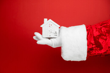 Santa hand holds house gift. Present for the New Year. Santa holding in hands house property insurance, credit loan, bank investment i