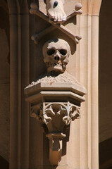 Sandstone skull sculpture with bones on a gate with neo-gothic tracery at the castle church in the old town of Meisenheim in Germany © float