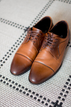 A pair of brown male shoes on a white floor close up