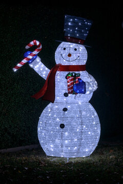 Blow-up Snowman wearing hat and scarf and holding candy cane and gift.