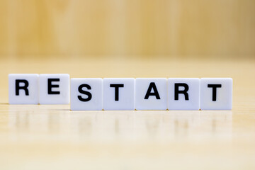 A row of small white plastic tiles, containing the letters forming the word restart, to represent...