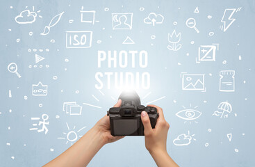Hand taking picture with digital camera and PHOTO STUDIO inscription, camera settings concept