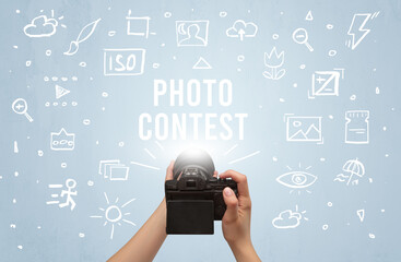 Hand taking picture with digital camera and PHOTO CONTEST inscription, camera settings concept