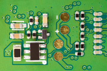 Green electronic circuit, with gold electrical contacts and various electrical components connected...