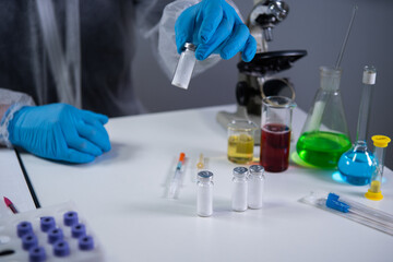 Fototapeta premium Development and search for drug for coronavirus. Chemist examining ampoule of powdered antibiotic for injection. Treating bacterial infection with medications. Covid 19 health and treatment concept