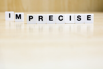 A row of small white plastic tiles, containing the letters forming the word precise, to represents the concept of the transformation of the transition from imprecise to precise.