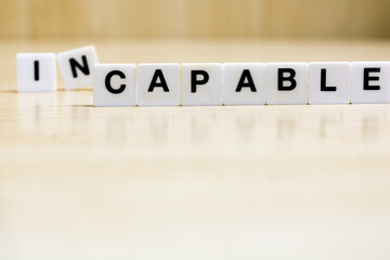 A row of small white plastic tiles, containing the letters forming the word capable, to represents the concept of acquiring competence and skills.