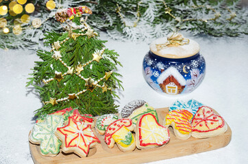 Homemade shaped cookies with multicolored icing on the background of scattered powdered sugar and Christmas decorations. Selective focus