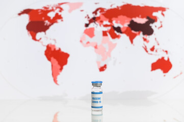 A glass bottle with a coronavirus, covid, sars vaccine with a world map on the background. Close-up...