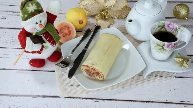 Roll cake, Brazilian traditional sweet. Next to a cup of coffee, guavas and Christmas decoration (panoramic).