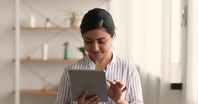 Indian 30s woman internet shopper using tablet enjoy comfort easy online shopping on retail website service, good discounts, lower prices, save money, check tracking. Modern tech buy from home concept