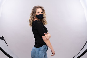 Junge Frau 27 Jahre alt mit NasenMundschutzmaske im schwarzen Pullover